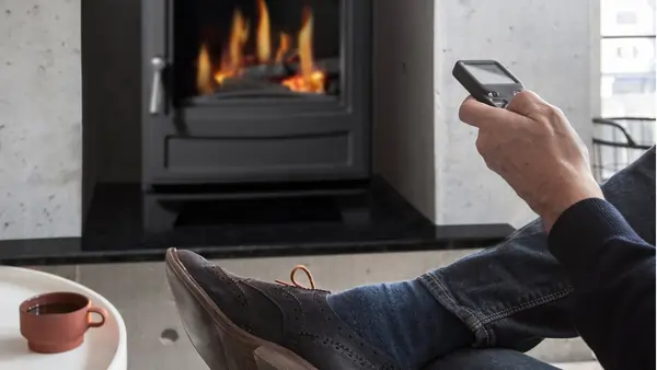Man operates Arada Ecoburn Gas stove with a remote control