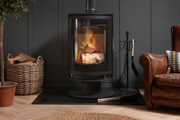 Arda Hoxton stove on optional pedestal next to cosy armchair
